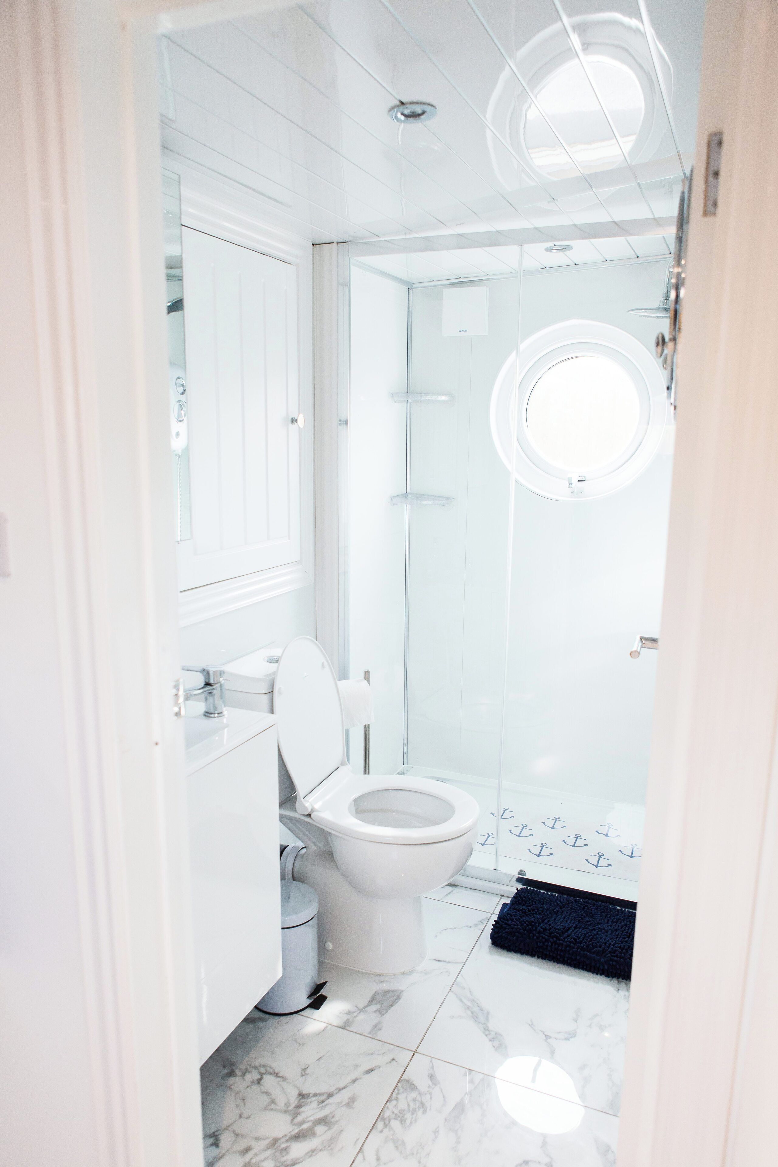 Une salle de bain moderne avec des toilettes blanches, un lavabo et une douche à parois de verre.