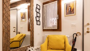 A room with a yellow armchair, a large mirror, a radiator, and a door with a wooden frame. - “Ea casa de mì - The Magic of Experiencing Venice” (Venezia)
