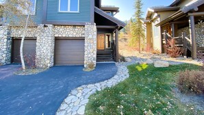 A two-story house with stone cladding, a stone entrance, and a covered porch. - Snowcreek V 774 Gorgeous Mountain Views with Private Garage, Washer Dryer and Gas Grill by RedAwning (Mammoth Lakes)