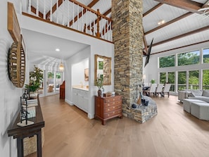 A spacious interior with a high ceiling, stone fireplace, and large windows. - Riverfront Sanctuary | Your Mountain Getaway (Burnsville)