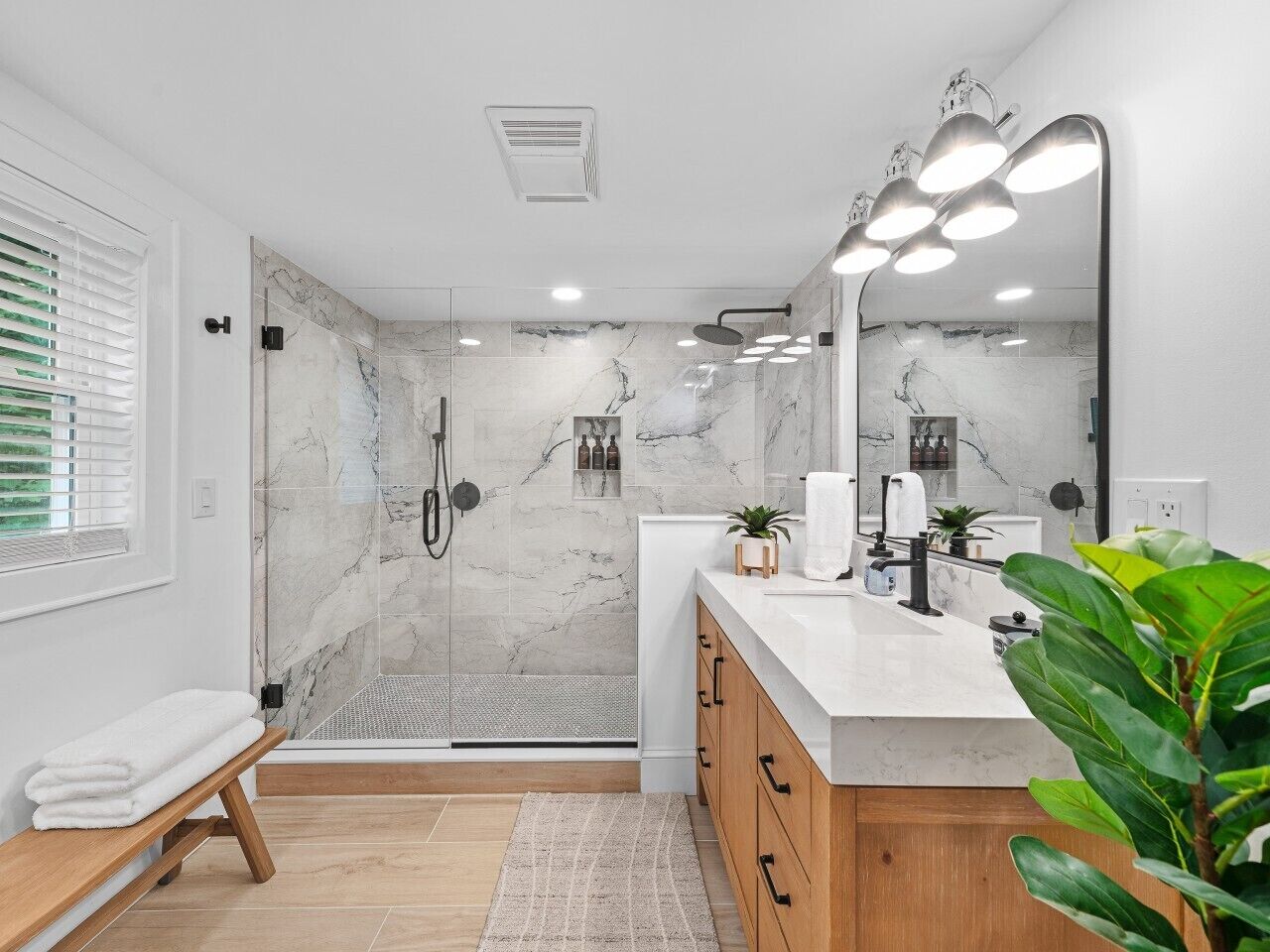 Een moderne badkamer met douche, wastafel en een grote spiegel.
