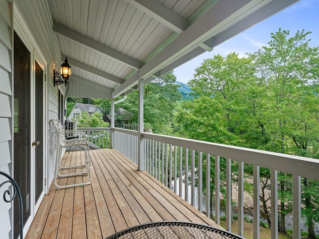 Une terrasse en bois avec une rambarde, une chaise et un lampadaire.