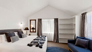 Une chambre d’hôtel moderne avec un grand lit, un canapé bleu, une armoire et une fenêtre avec des rideaux.
