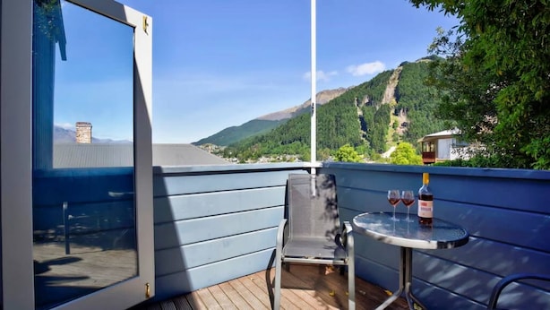Un balcon avec une table, deux chaises et une bouteille de vin.