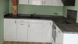 A compact kitchen with white cabinets, a black countertop, and a wooden ceiling beam. - The Magic of the Baltic Sea at Ludwigsburg Palace – Experience Nature, the Sea, and Culture (Loissin OT Ludwigsburg)