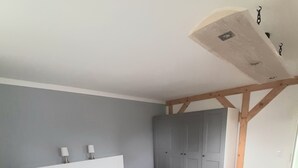 A bedroom with a white bed, grey walls, a grey wardrobe, and a wooden ceiling. - The Magic of the Baltic Sea at Ludwigsburg Palace – Experience Nature, the Sea, and Culture (Loissin OT Ludwigsburg)