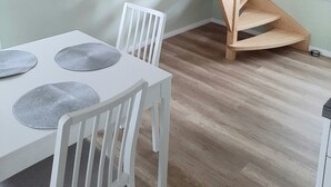 A wooden staircase in a room with a white table and chairs, a window, and a light green wall. - The Magic of the Baltic Sea at Ludwigsburg Palace – Experience Nature, the Sea, and Culture (Loissin OT Ludwigsburg)