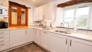 A modern kitchen with white cabinets, a built-in microwave, a toaster, and a wine bottle on the counter. - Barn End - Three Bedroom House, Sleeps 6 (Skelwith)