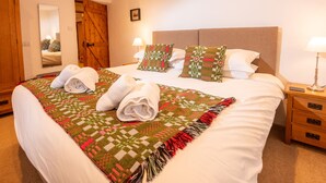 A neatly made bed with a patterned blanket, two pillows, and rolled towels. - Barn End - Three Bedroom House, Sleeps 6 (Skelwith)