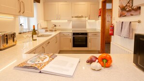 A modern kitchen with a built-in oven, a toaster, and a wine bottle on the counter. - Barn End - Three Bedroom House, Sleeps 6 (Skelwith)