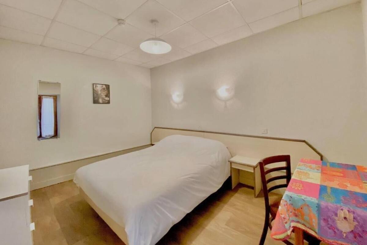Ein Schlafzimmer mit einem Bett, einem Schreibtisch, einem Stuhl und einem kleinen Tisch mit farbenfroher Tischdecke.