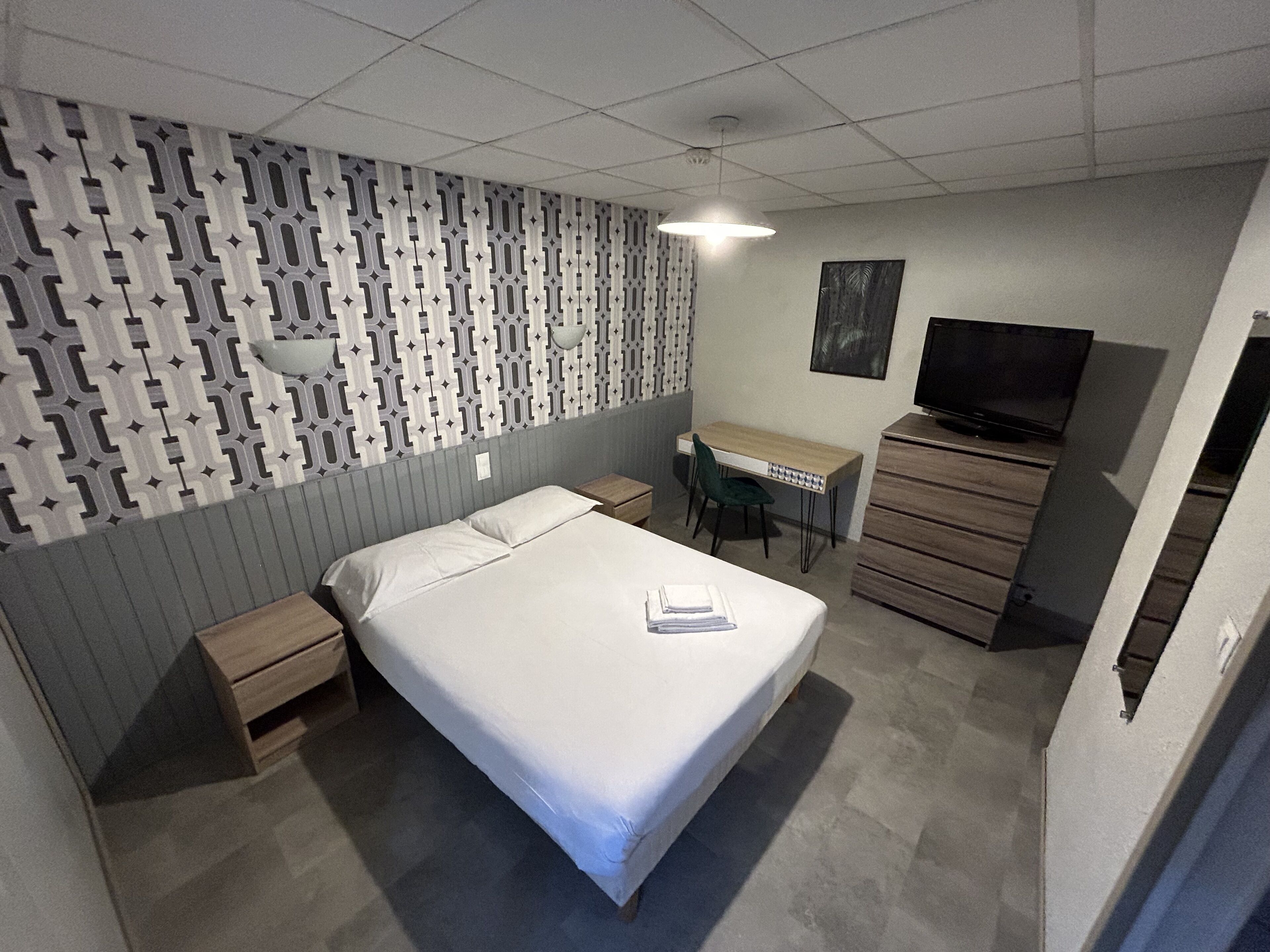 Ein Schlafzimmer mit einem Bett, einem Schreibtisch, einem Sessel, einem Fernseher und einer Kommode.