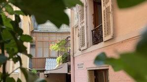 Un callejón estrecho flanqueado por edificios, con balcones adornados con plantas y un letrero de hotel y restaurante.
