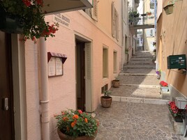 Um beco estreito de paralelepípedos, com um edifício à esquerda com a inscrição 