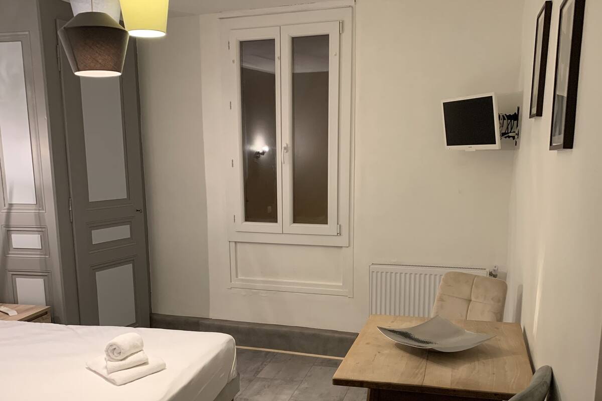 Ein Schlafzimmer mit einem Bett, einem Schreibtisch, einem Stuhl, einem Fenster und einem Fernseher.