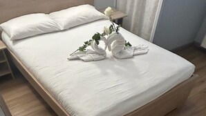 Una cama bien hecha con sábanas blancas y un arreglo floral de rosas encima.