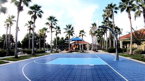 A basketball court with a blue surface, surrounded by palm trees and a gazebo. - Fresh Decor With Hardwood Floors Huge Private Pool Area CDC Standards 4tv121 (Kissimmee)