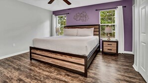 A bedroom with a wooden bed, a ceiling fan, a nightstand, and a window with curtains. - Fresh Decor With Hardwood Floors Huge Private Pool Area CDC Standards 4tv121 (Kissimmee)
