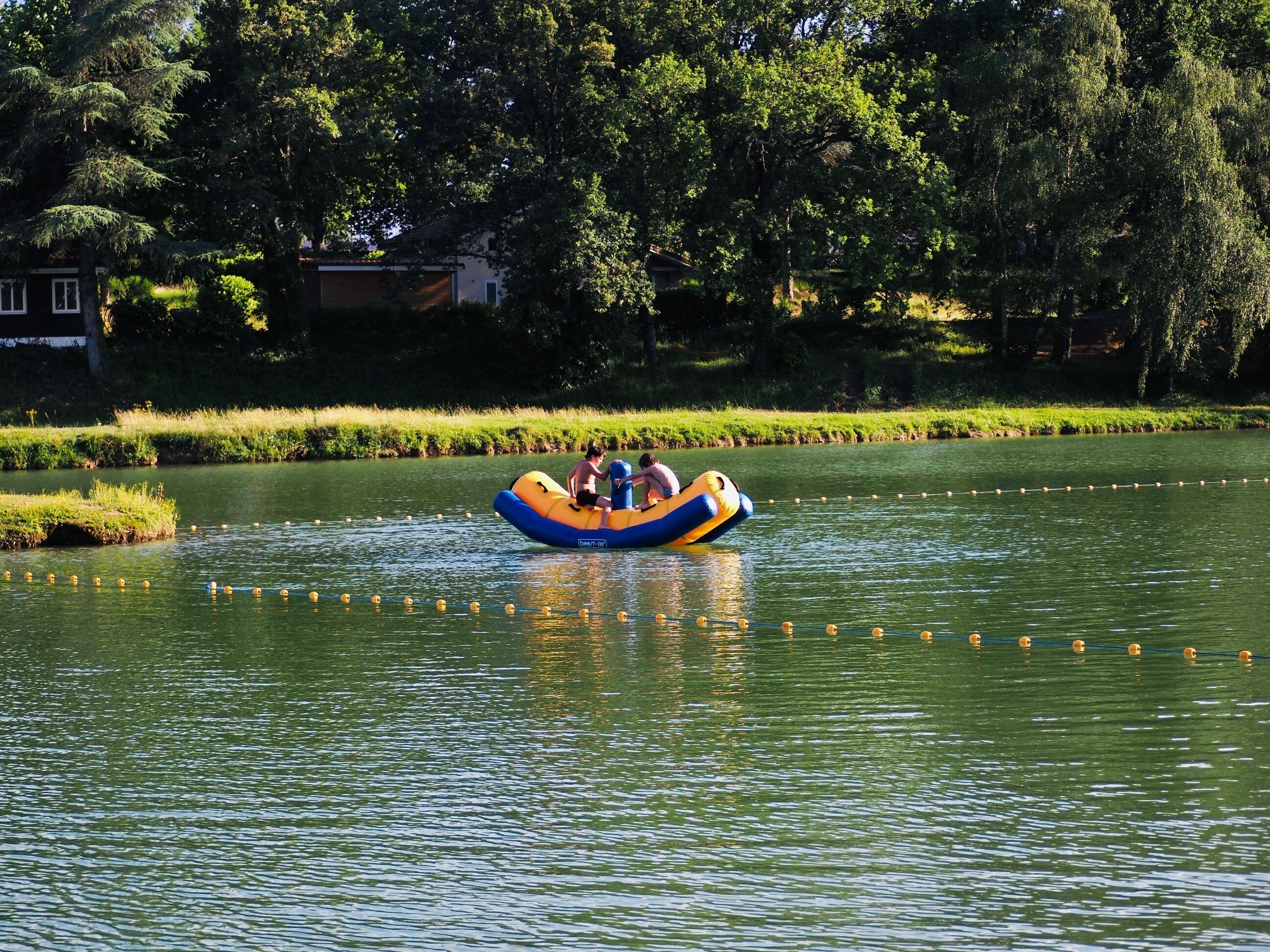 Una persona en un bote inflable azul y amarillo en un río tranquilo.