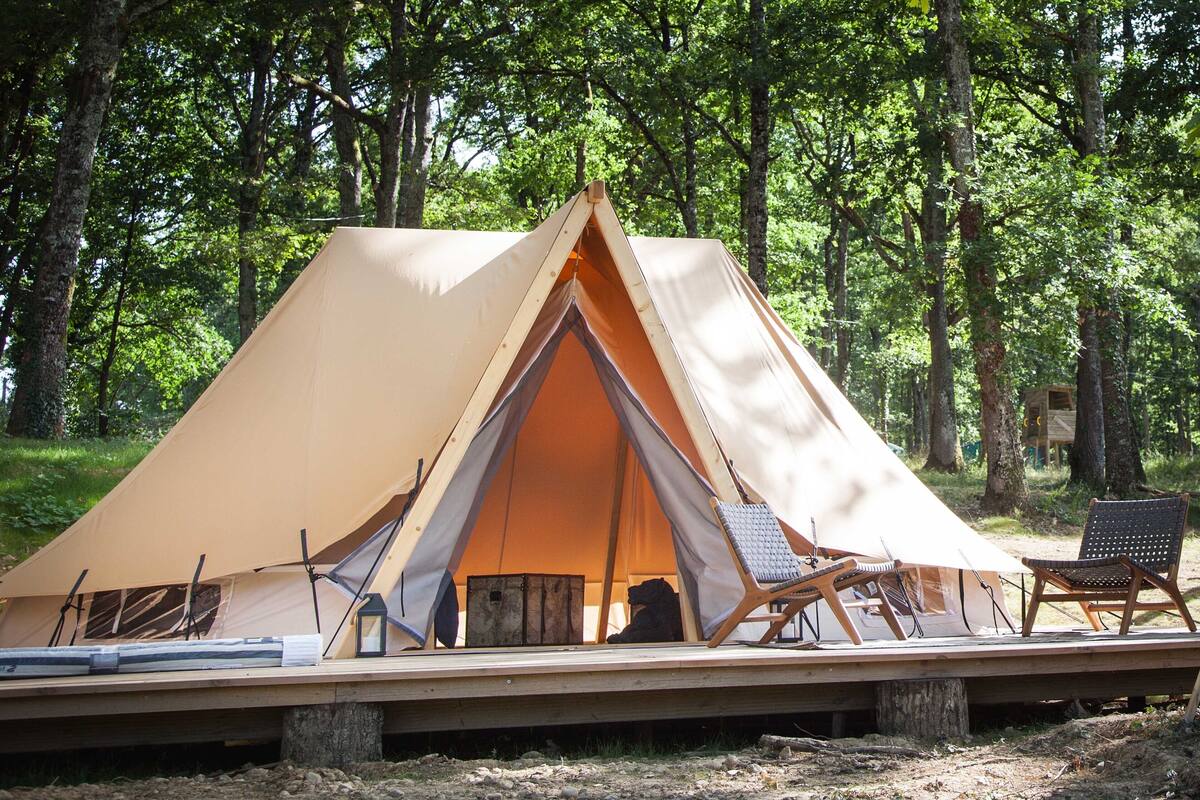 A tent with a wooden deck, two chairs, and a table.