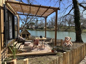 A wooden deck with a pergola, outdoor seating, and a large teddy bear. - Whaka Lodge (Seissan)