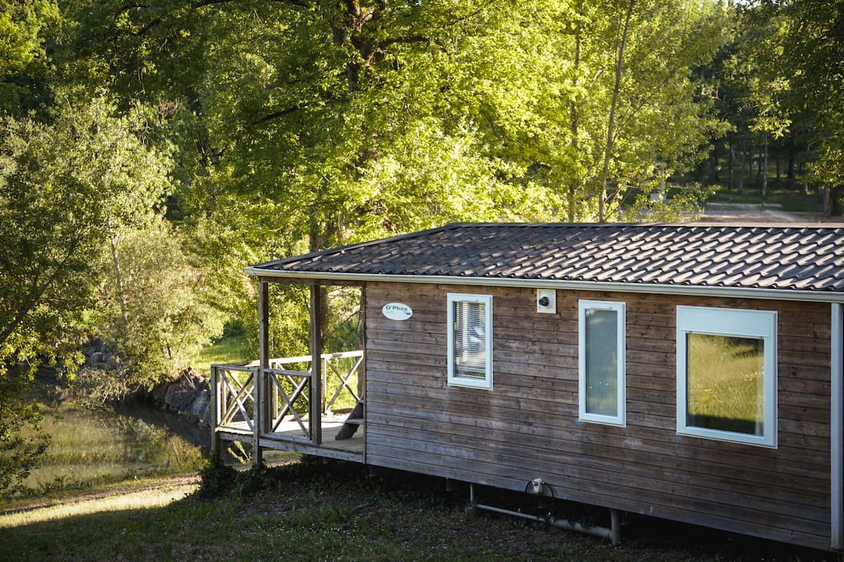 A wooden cabin with a porch, a small deck, and a sign that reads "O'Phéa".