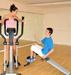 Une salle de sport équipée de matériel d’exercice, notamment un vélo d’appartement et un appareil d’aviron.