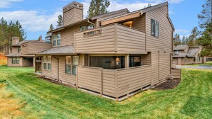 Una casa moderna de varios pisos con techo plano, ventanas amplias y un espacio exterior cubierto.