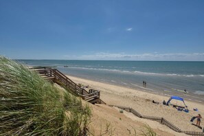 Una spiaggia con una passerella di legno, la sabbia e l'oceano.