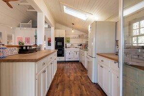 Une cuisine avec un plancher en bois, des meubles de cuisine blancs, une cuisinière et un réfrigérateur.