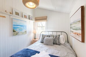 Una camera da letto con un letto, una finestra e opere d'arte appese al muro.