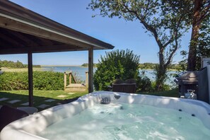 A hot tub with a view of a lake, a covered patio, and outdoor furniture. - Seaside Retreat w/ Private Beach Landing! (Eastham)