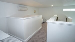 Ein geräumiges Zimmer mit hoher Decke, weißen Wänden und einer festen Sitzbank an einer Wand.