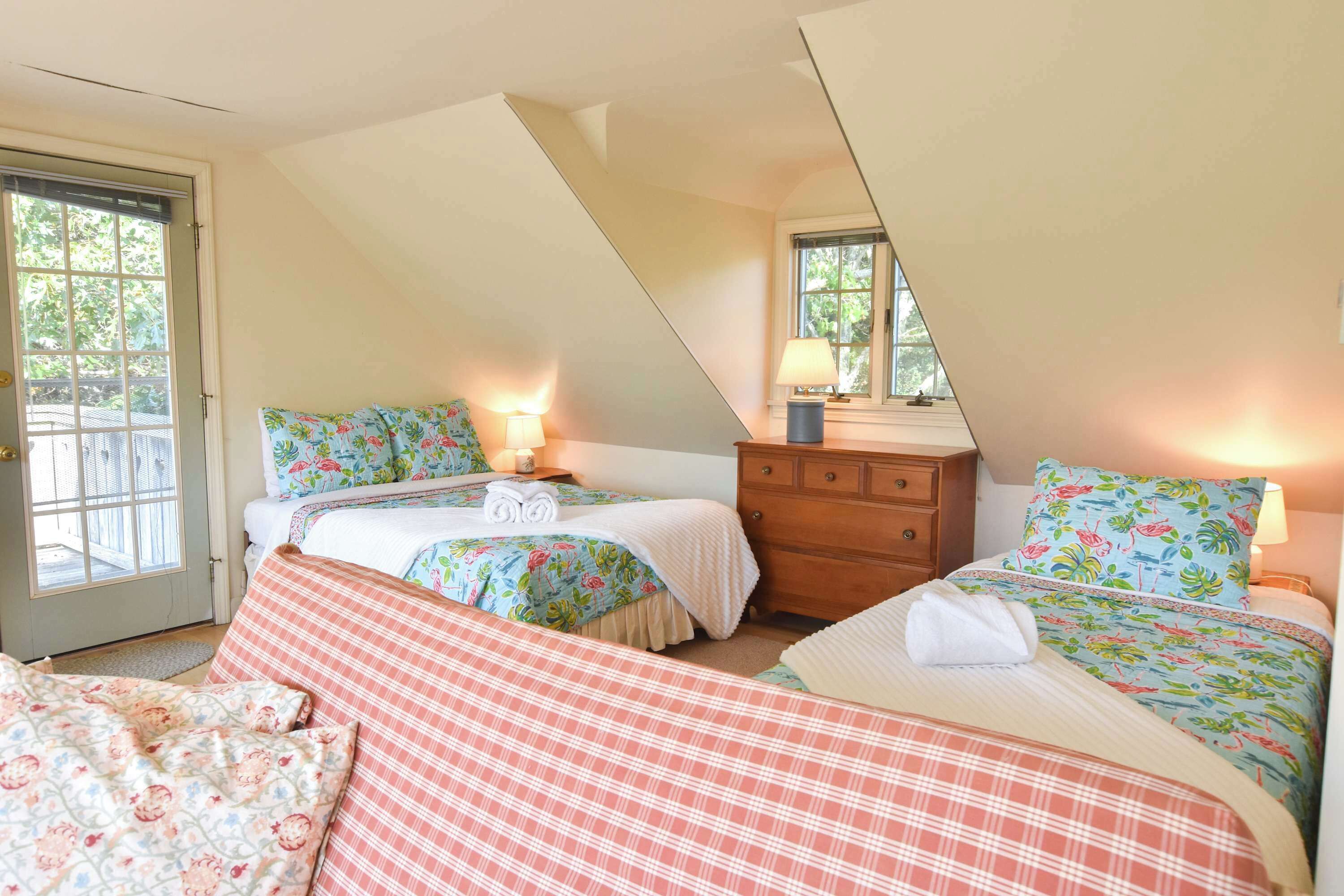 Ein Schlafzimmer mit zwei Betten, einem Schminktisch und einer Tür, die nach draußen führt.