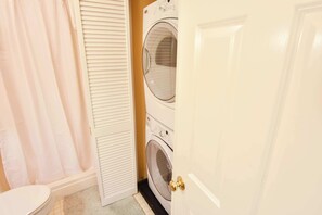 A laundry room with a washing machine, a dryer, and a shower curtain.
