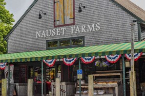 A building with a sign reading "NAUSEAT FARMS" and a green awning with red and white decorations.