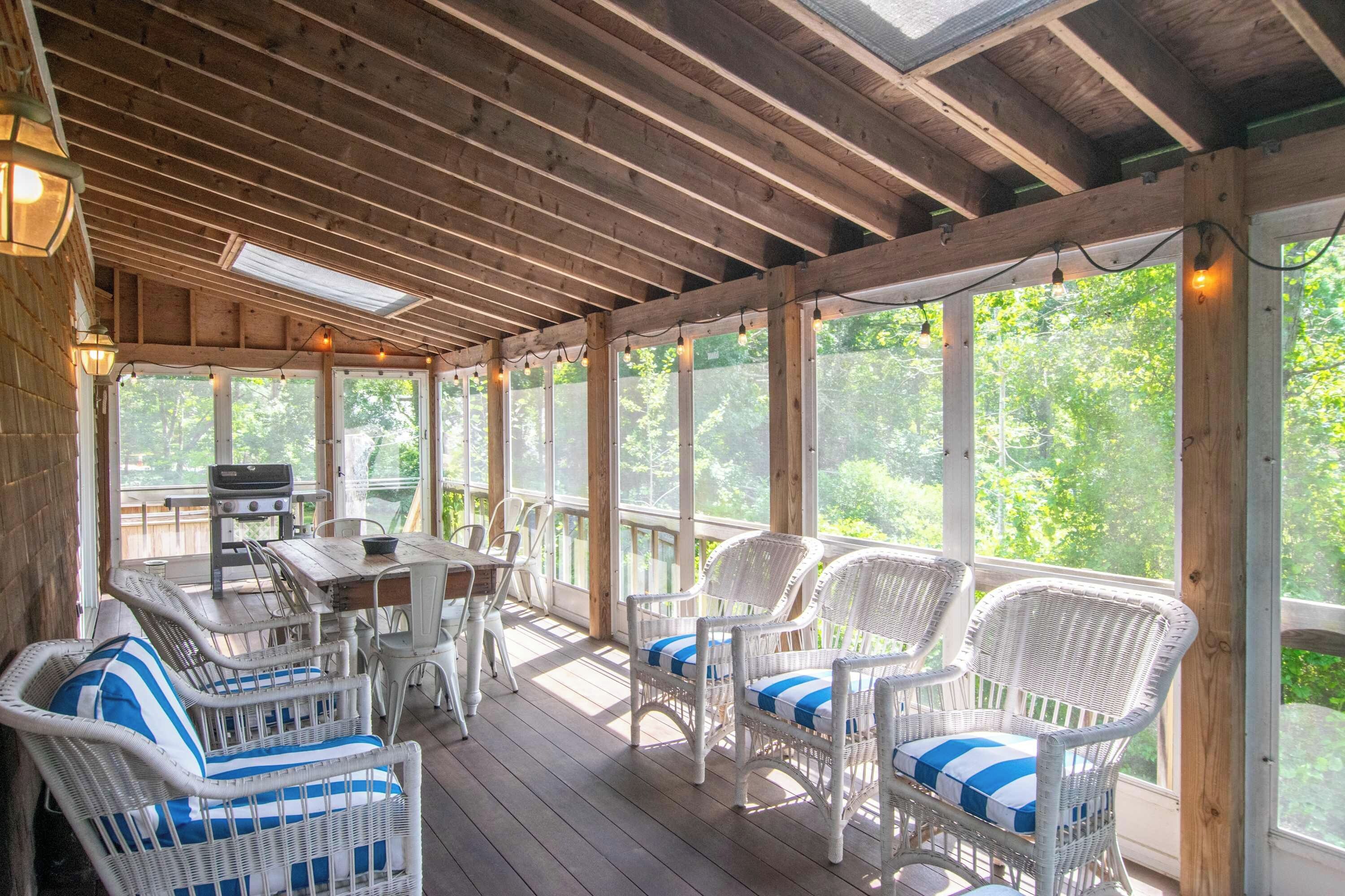 A covered outdoor seating area with wicker furniture and a grill.