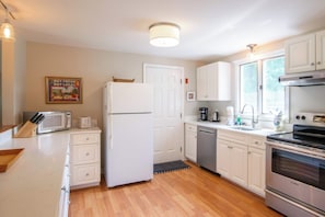 A kitchen with white cabinets, a refrigerator, a microwave, a coffee maker, and a Bosch oven.