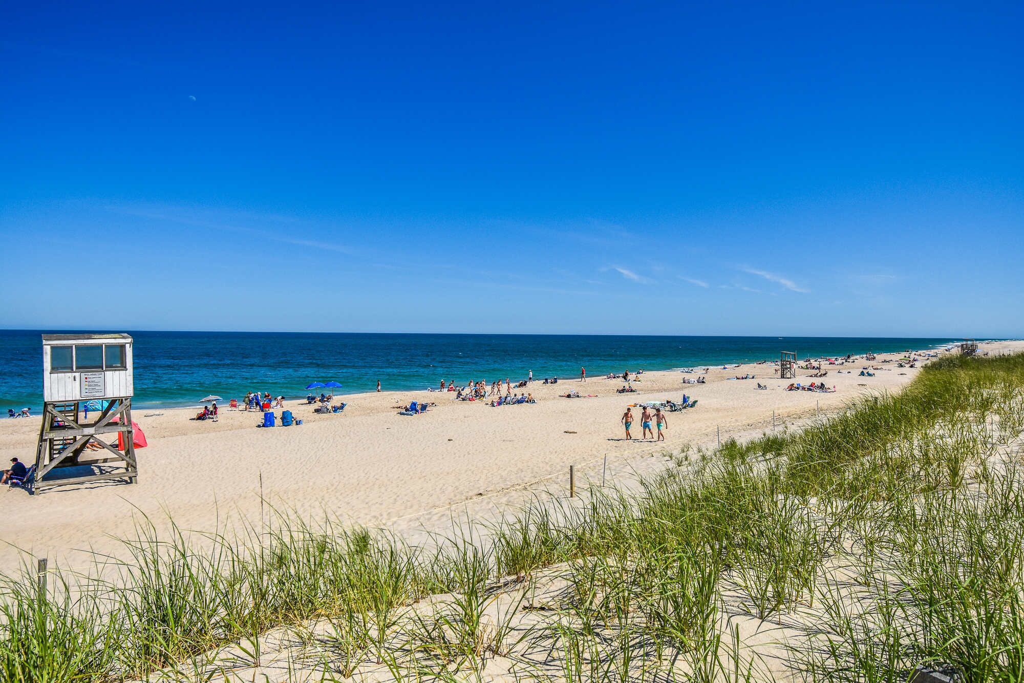 Une plage avec une tour de surveillance pour les sauveteurs, un rivage sablonneux et un ciel bleu dégagé.