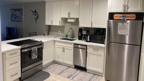 A modern kitchen with white cabinets, stainless steel appliances, and a tiled backsplash. - Relax and Rejuvenate in the Heart of Kona. Minutes walk to town! (Kailua-Kona)