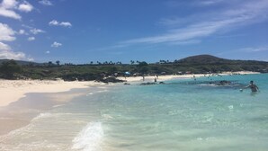 A beach with clear turquoise water, white sand, and a few people in the distance. - Relax and Rejuvenate in the Heart of Kona. Minutes walk to town! (Kailua-Kona)