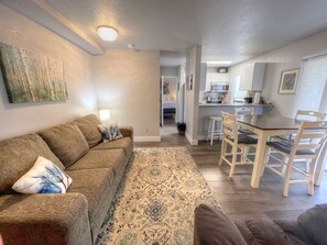 A living room with a sofa, a patterned rug, and a dining area with a table and chairs.