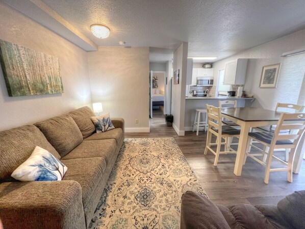 A living room with a sofa, a patterned rug, and a dining area with a table and chairs. - LOCATION! Base Area Trails Right Outside your Door! GREAT RATES! (Mt. Crested Butte)