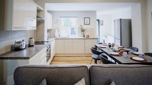 A modern kitchen with a dining area, featuring a kitchen island, built-in appliances, and a view of the outdoors.