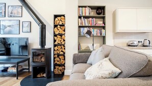 A cozy living room with a fireplace, a sofa, a bookshelf, and a television.