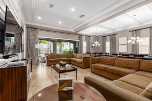 Relax in this stylish living room with a large sofa, coffee table, and dining area, offering a view of the outdoors.