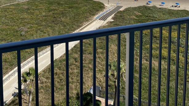A beach view from a balcony with a railing, a sandy beach, and the ocean. -  Cozy Beach Condo Awaits on Padre Island! (South Padre Island)