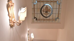 A staircase with a red carpet, white walls, and a stained glass window above. - At Handel's Refreshment House (Vignanello)