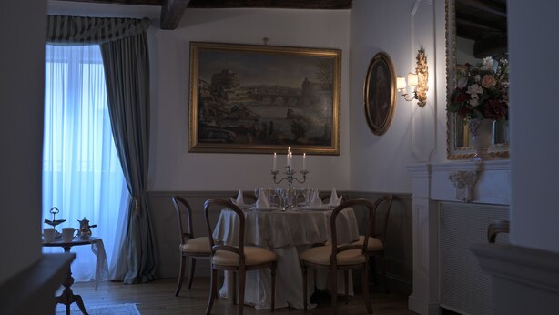 A dining room with a table set for four, a chandelier, and a painting on the wall. - At Handel's Refreshment House (Vignanello)