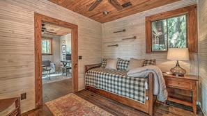 Ein gemütliches Blockhaus-Interieur mit einem Holzbett, einem Schreibtisch und einem Essbereich.